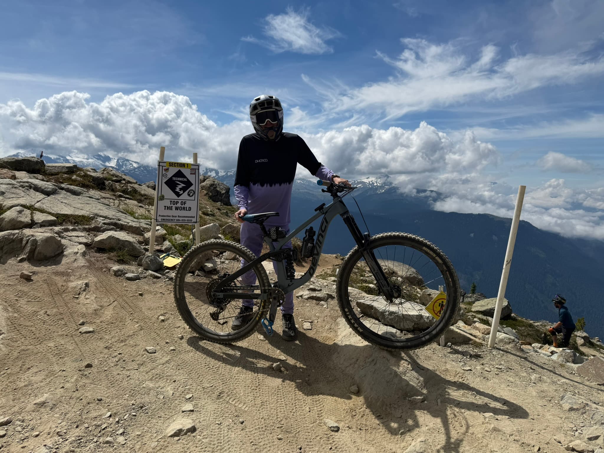 Adam Glover standing with a mountain bike above the clouds.